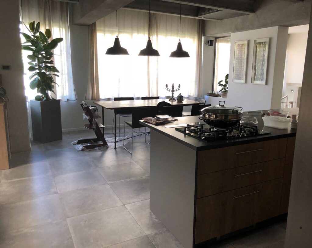 Loft di design moderno in stile minimal con cucina ad isola, vetrate, cemento lisciato e parquet a Milano per foto, video, eventi