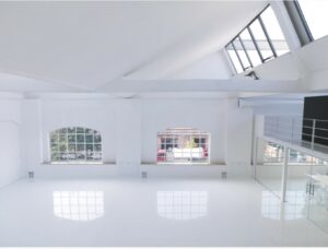 Spazio industriale in stile total white con vetrate, cemento lisciato e parquet a Milano per foto, video, eventi