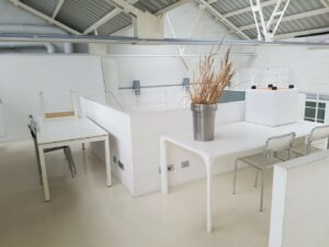 Spazio industriale in stile total white con vetrate, cemento lisciato e parquet a Milano per foto, video, eventi