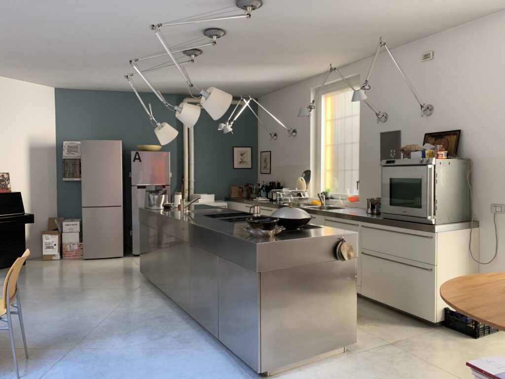 Loft minimal con cucina ad isola e travi a vista a Milano per foto video eventi